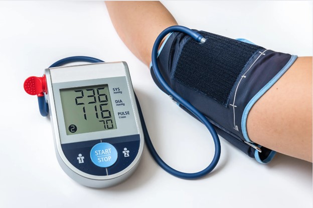 An image showing a blood pressure monitor on an arm and a glucose meter with a reading displayed next to it, both resting on a surface, indicating a health-related setting.