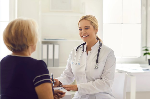 The image depicts a medical professional interacting with an elderly patient in an indoor setting.