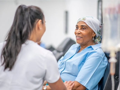 This image depicts a woman in a hospital setting receiving medical treatment, with a healthcare professional attending to her.