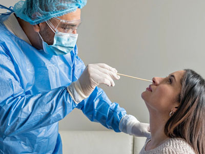 A healthcare professional administers a nasal swab to a patient in a medical setting.