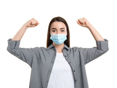 A person wearing a face mask flexes their arms while standing against a white background.