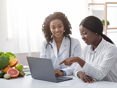 The image shows two individuals at a table with a laptop, surrounded by fresh produce, with a smiley face emoji on top.