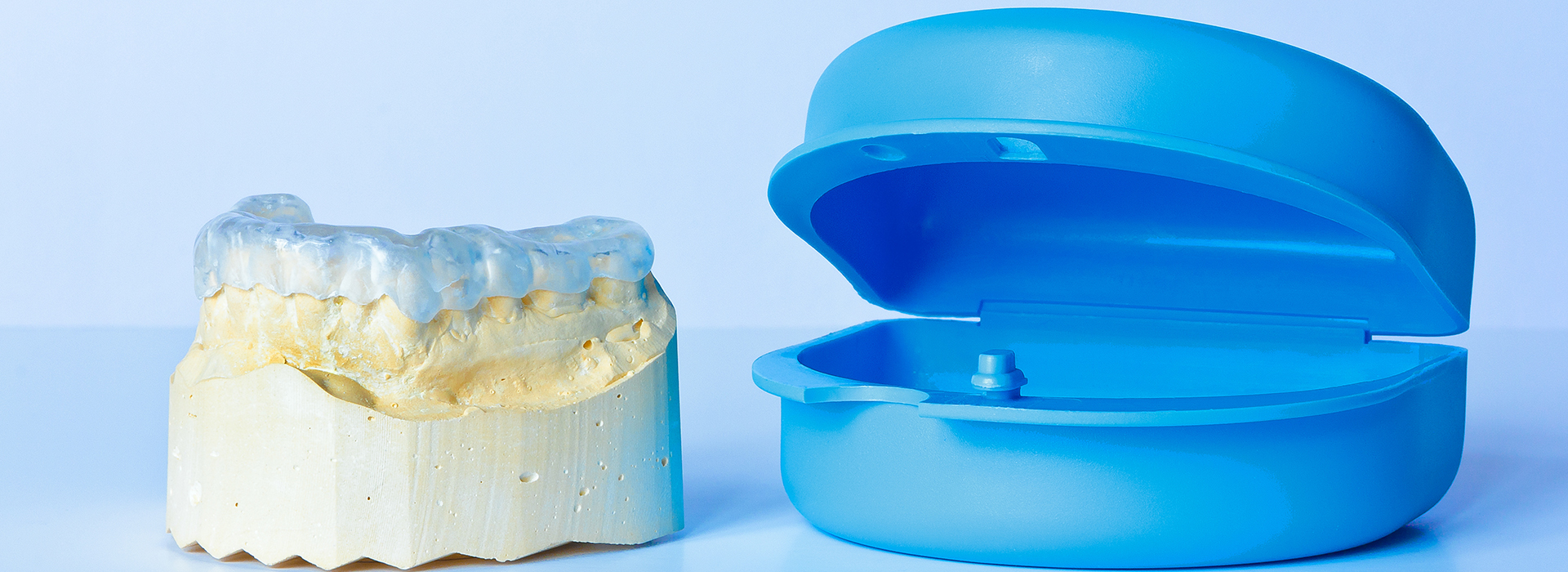 The image displays two dental implants a blue toothbrush-shaped object and a beige cylindrical object, both of which appear to be artificial teeth replacements against a white background.