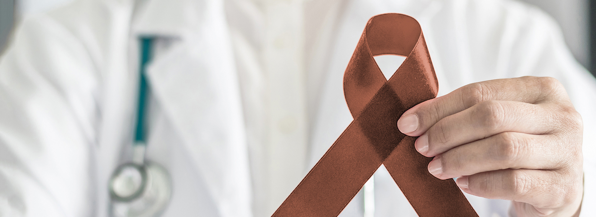 The image shows a medical professional holding up a red ribbon with an AIDS symbol on it, set against a background that includes the text AIDS and HIV.